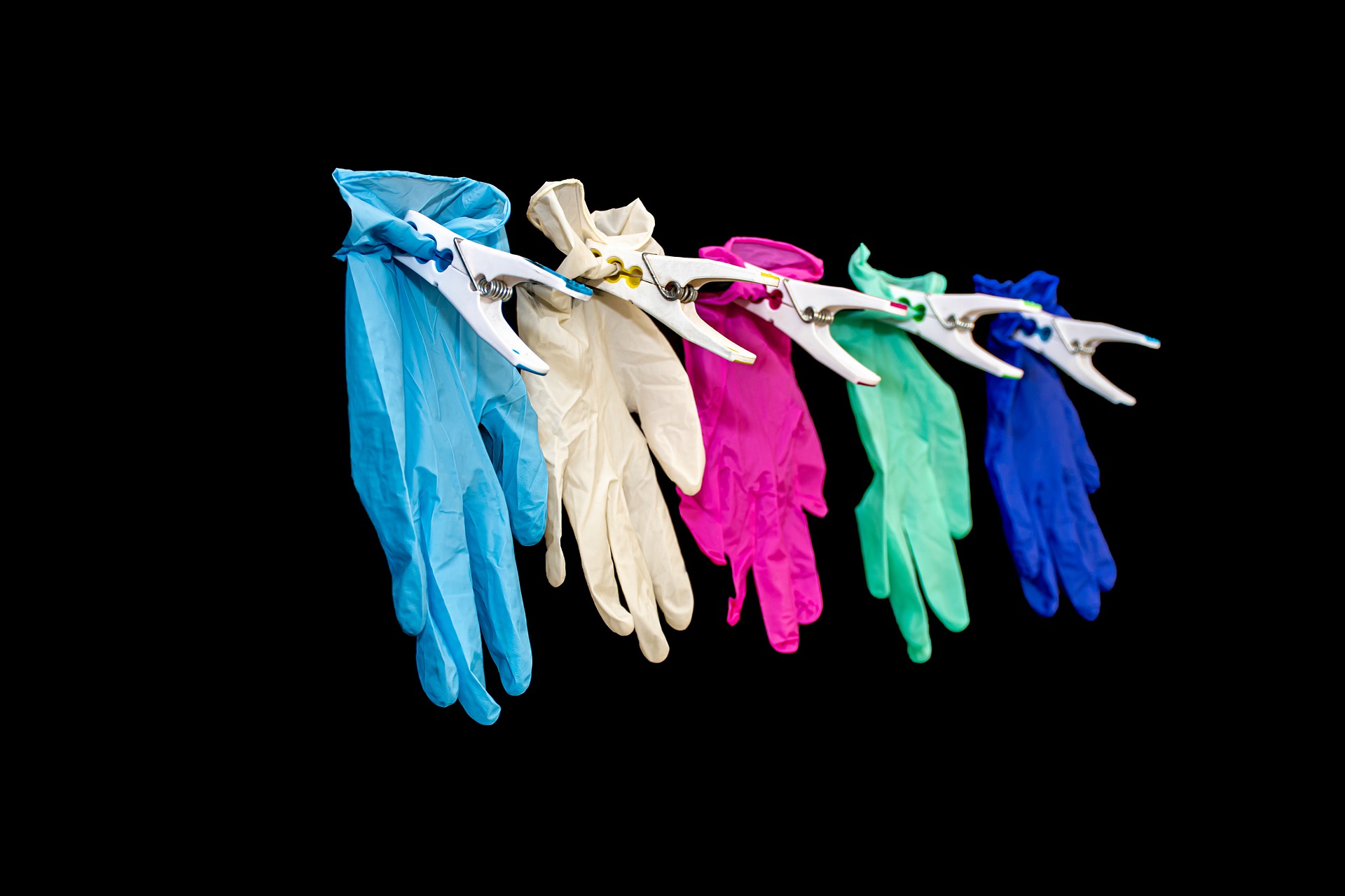 Colourful gloves pegged in a line on a black background